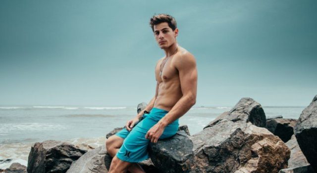 мужчина сидит на камнях на берегу моря