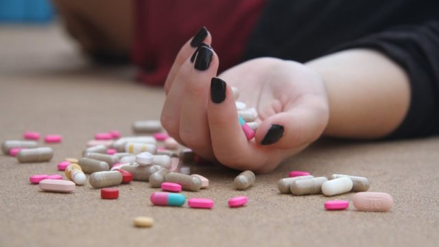 женская рука на полу с таблетками