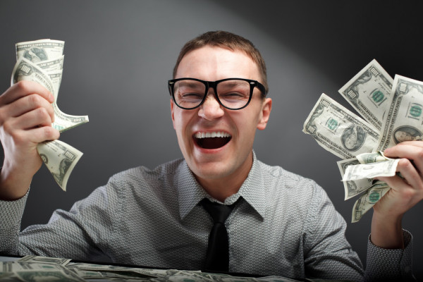 парень в очках улыбается с долларами в руках