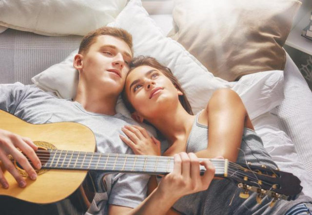 парень с гитарой и девушка лежат на кровати
