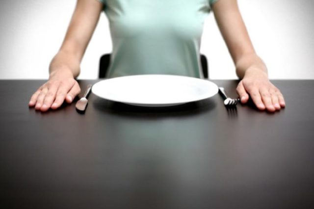 девушка сидит за столом с пустой тарелкой