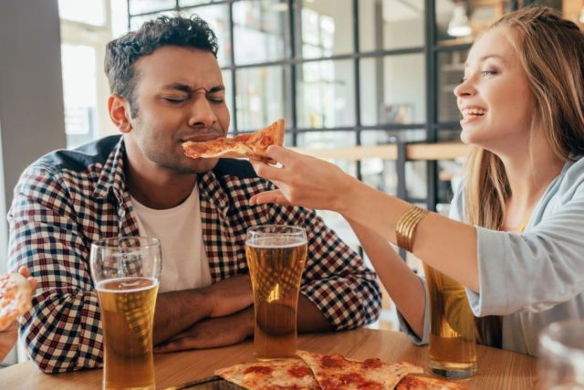женщина кормит пиццей мужчину