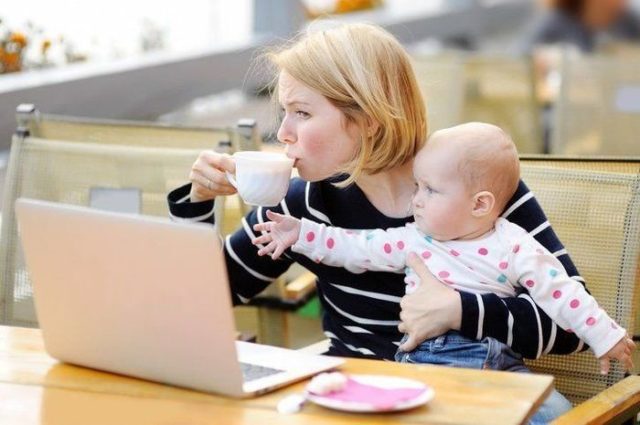 женщина с ребенком на руках перед ноутбуком