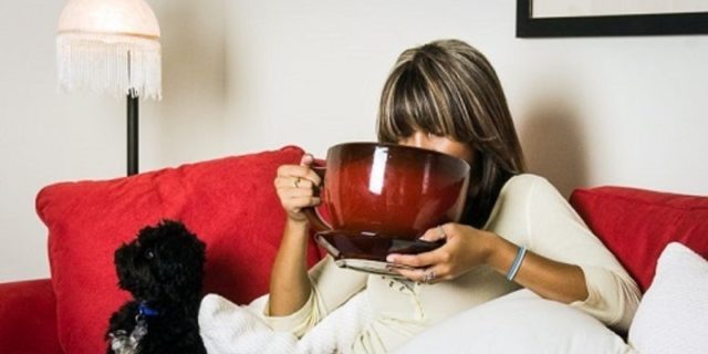 женщина с большой чашкой кофе на диване