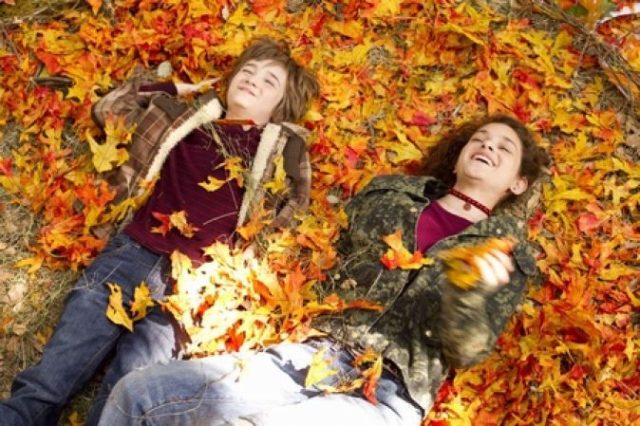 женщина и мальчик лежат в осенних листьях