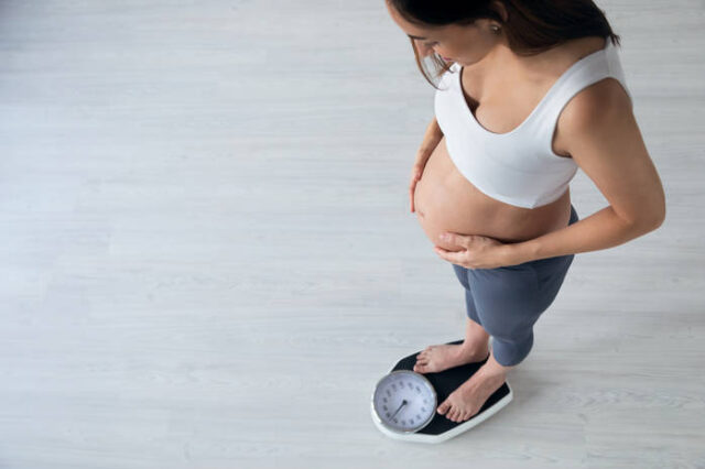 беременная девушка стоит на весах