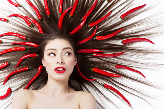 стручки красного перца в волосах девушки