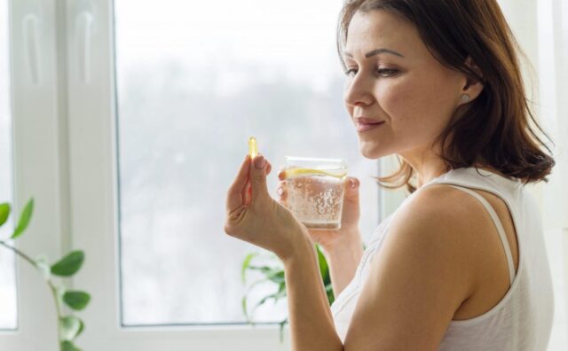женщина держит стакан с водой и витамины