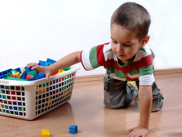 мальчик складывает игрушки в корзину