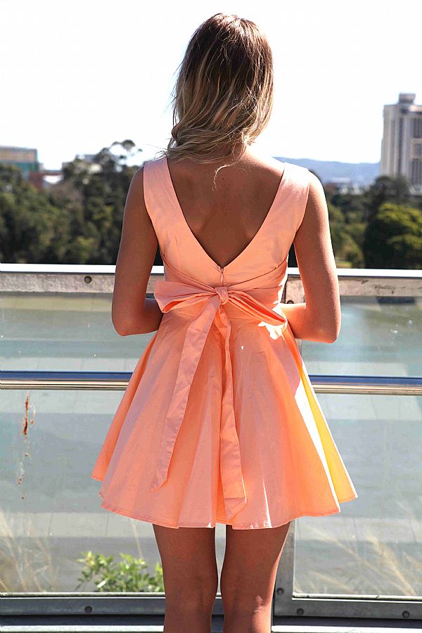 девушка в персиковом платье с открытой спиной и бантом