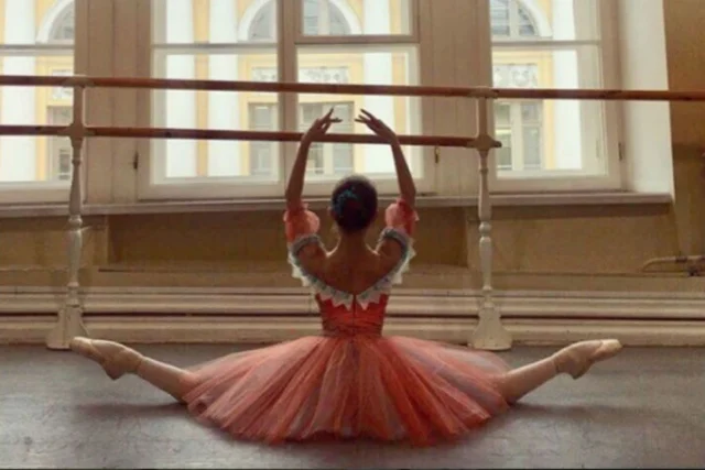 балерина сидит на шпагате в розовом платье