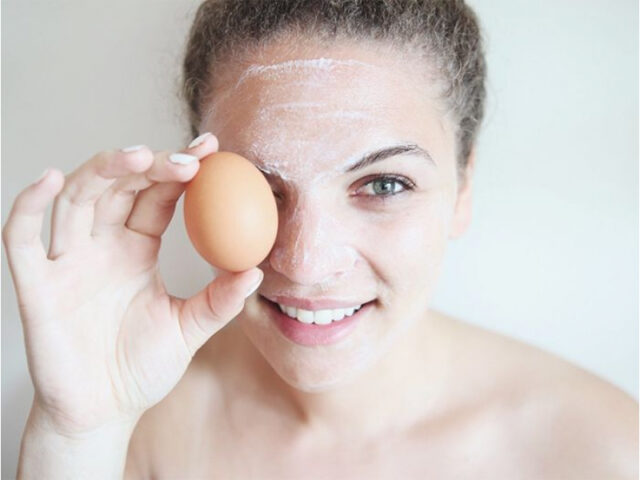 девушка с маской на лице держит в руке яйцо